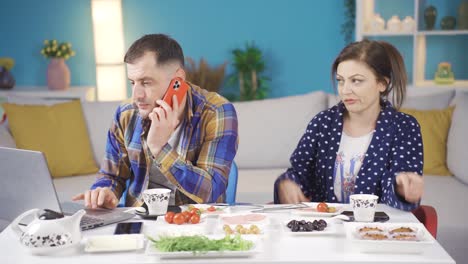 The-married-couple-is-having-breakfast-at-breakfast,-the-man-who-is-busy-about-his-work-is-talking-on-the-phones-and-his-wife-is-not-happy-about-this-event.